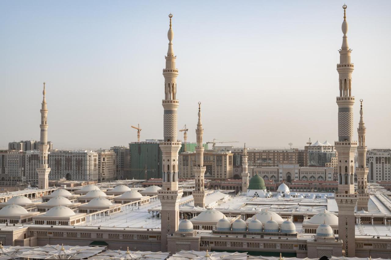 Готель Sofitel Shahd Al Madinah Medina Екстер'єр фото The photo depicts a view of an Islamic mosque complex with several prominent minarets. The architectural style features a blend of intricate designs and large, domed roofs. The scene appears to be set in a modern urban environment, with construction 