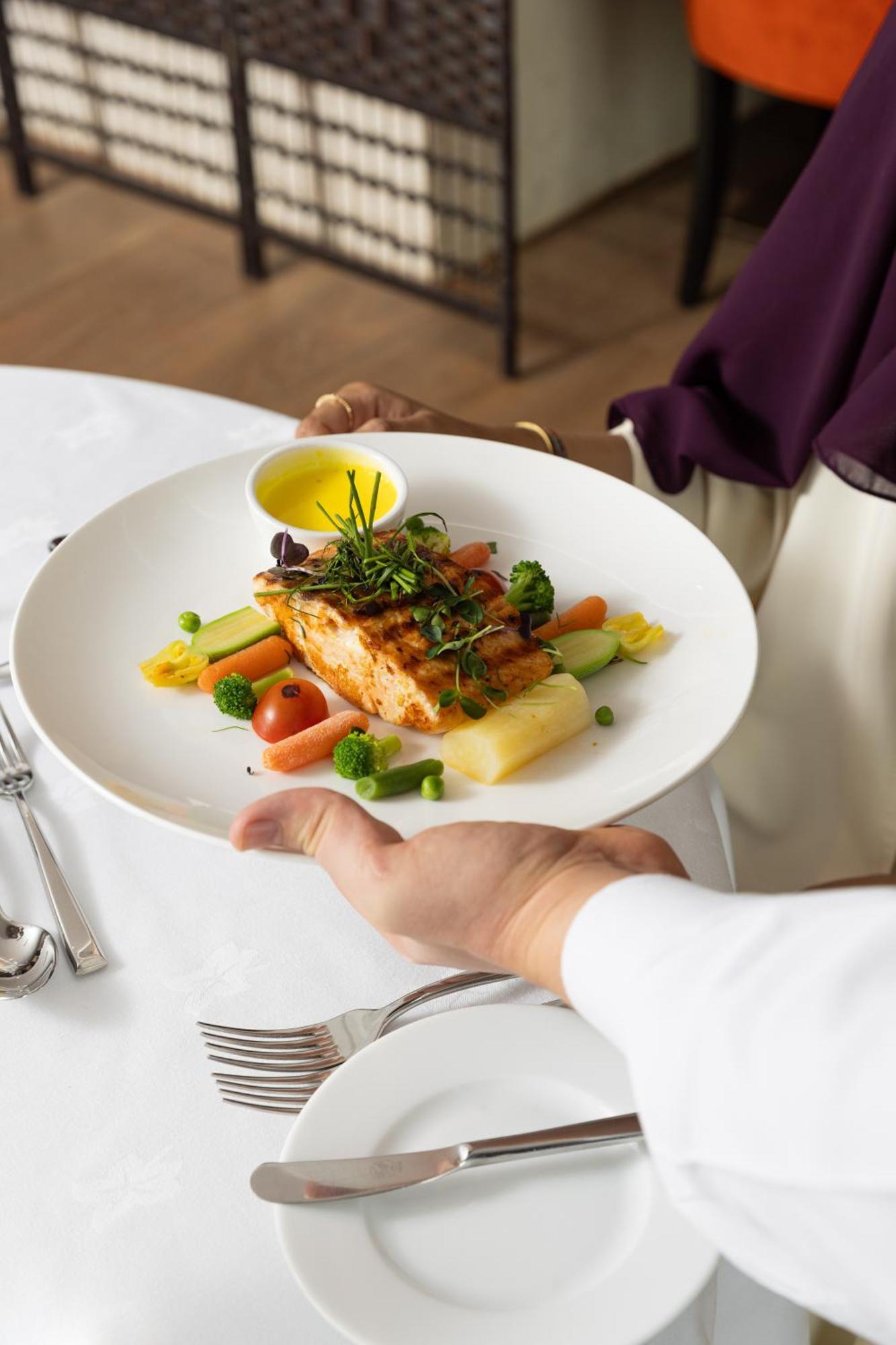 Готель Sofitel Shahd Al Madinah Medina Екстер'єр фото The photo shows a plate of food being presented. The dish features a piece of grilled salmon on a bed of vegetables, including small tomatoes, green peas, and other colorful vegetables. There is also a drizzle of yellow sauce, likely a dressing or oi